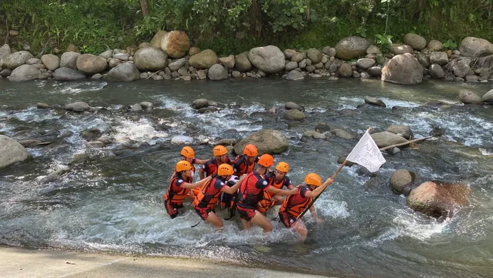 Trainees crossing a rocky river together