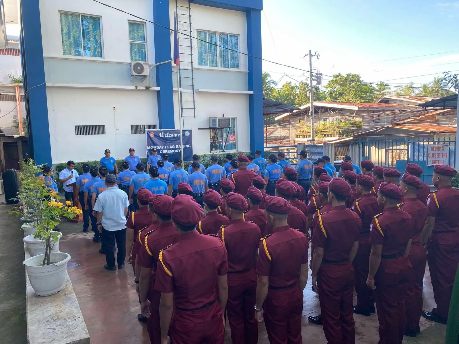 Trainees and police personnel gathered outdoors for a flag-raising ceremony